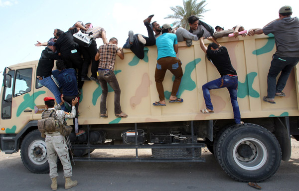 伊拉克志愿军爬上巴格达募兵中心外的军用卡车，准备参与对抗叛军